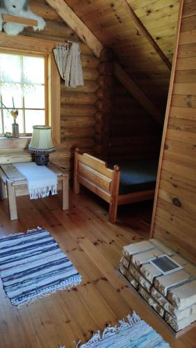 um chalé de madeira com uma cama e uma mesa em Gojaus smukle em Molėtai