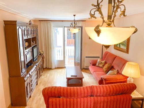 sala de estar con sofá rojo y TV en Apartamento Los Leones, en Berlanga de Duero