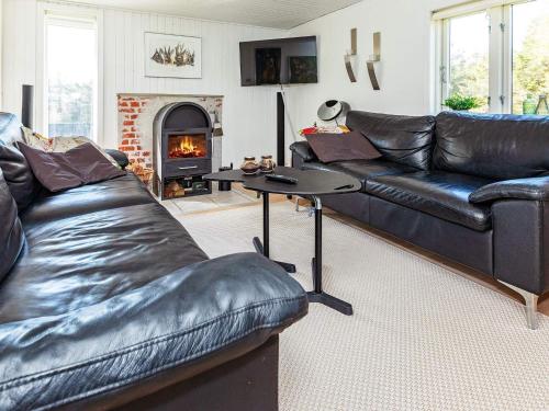 sala de estar con sofá de cuero y chimenea en 6 person holiday home in Blokhus, en Blokhus