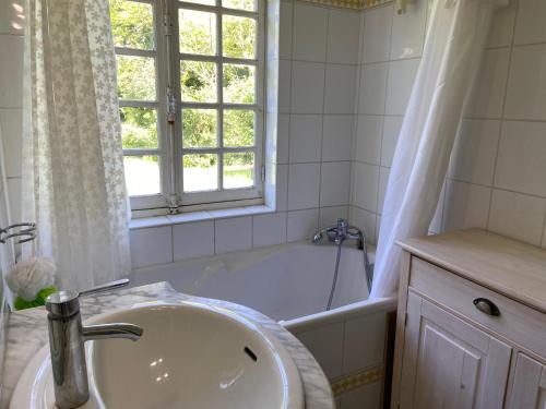 La salle de bains est pourvue d'un lavabo et d'une baignoire avec fenêtre. dans l'établissement Maison de Campagne Baie de Somme 17 couchages, à Tours-en-Vimeu