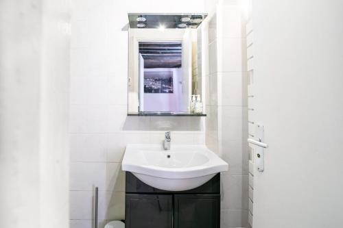 ein weißes Badezimmer mit einem Waschbecken und einem Spiegel in der Unterkunft Appartement Mouffetard in Paris