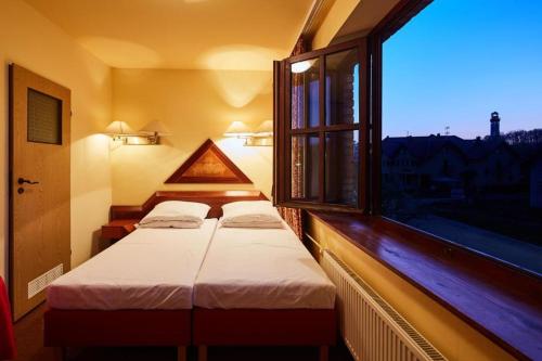 2 Betten in einem Zimmer mit einem großen Fenster in der Unterkunft Dom Wczasowy KORMORAN Niechorze - 300m od plaży in Niechorze