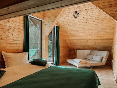 a bedroom in a wooden house with a bed and a couch at Cabana Laptici - statiunea Pestera-Padina, Bucegi in Sinaia
