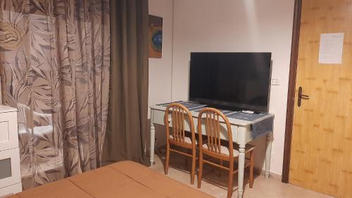 a room with a desk with a television and two chairs at Casa Bella in Gela