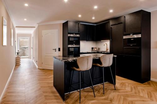 a kitchen with black cabinets and a island with bar stools at Altstadt Apartments in Friedrichstadt