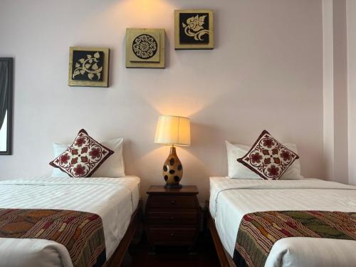 a bedroom with two beds and a lamp on a night stand at Pha Thai House in Chiang Mai