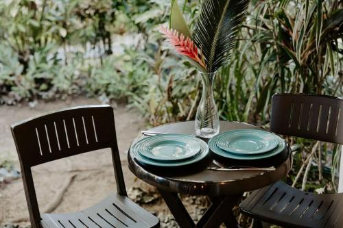 a table with plates and a vase with a flower on it at CoconutTree Bungalow of Villa Paraiso / Beachfront in Big Creek