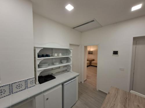 a white kitchen with white cabinets and a table at Le Roccette Mare Beach Hotel & Restaurant in Tropea