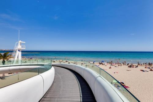 a boardwalk to the beach with people on the beach at HB Apartments - Luceros Luxury Loft in Alicante