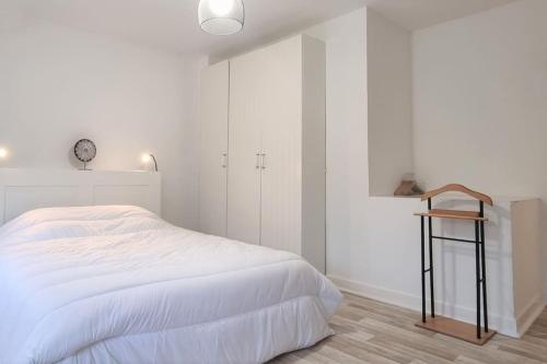 um quarto branco com uma cama e um relógio na parede em Apollinaire - Très jolie maison - Jardin - 3pers em Lille