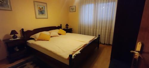 una camera da letto con un letto con cuscini gialli e una finestra di Apartmani Horvat - Varaždinske Toplice a Varaždinske Toplice
