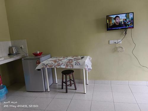 a kitchen with a table and a tv on the wall at ALZA BUDGET ROOMStay in Pantai Cenang