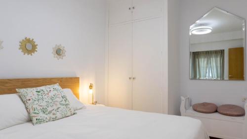 biała sypialnia z łóżkiem i lustrem w obiekcie Apartment Caleta Beach Málaga w Maladze