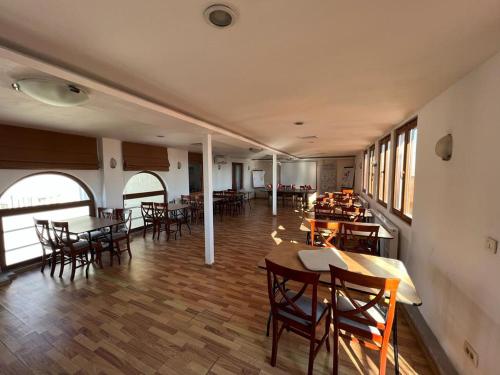 ein Esszimmer mit Tischen, Stühlen und Fenstern in der Unterkunft Hotel Andy in Bukarest