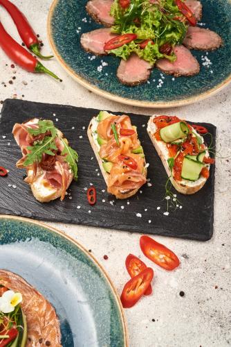 a table with plates of food with sandwiches and tomatoes at Sonata Hotel & Restaurant "готель Соната" in Lviv
