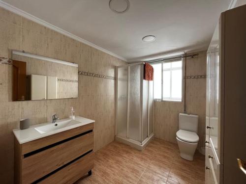 La salle de bains est pourvue d'un lavabo, de toilettes et d'un miroir. dans l'établissement Amplio y luminoso apartamento, à Sagonte