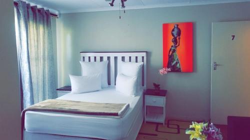 a bedroom with a white bed and a red painting at The Vine Guest House Potchefstroom in Potchefstroom