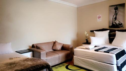 a bedroom with a couch and a chair in it at The Vine Guest House Potchefstroom in Potchefstroom
