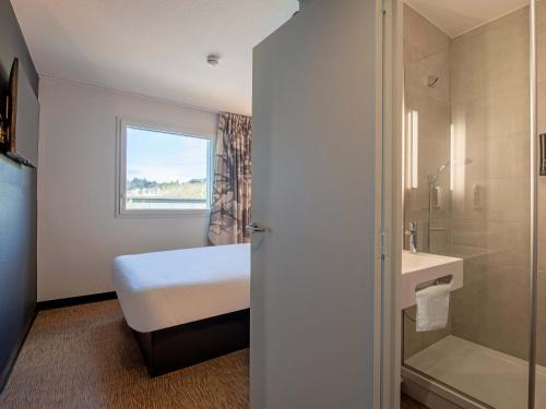 ランデルノーにあるB&B HOTEL Landerneau Bois Noirのベッドルーム1室(ベッド1台付)、バスルーム(シャワー付)が備わります。