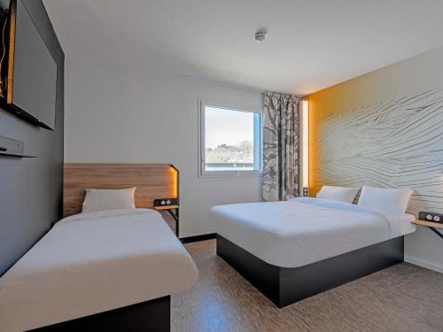 Cette chambre comprend 2 lits et une fenêtre. dans l'établissement B&B HOTEL Landerneau Bois Noir, à Landerneau