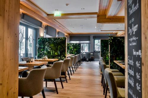 een restaurant met tafels, stoelen en planten bij Boutique Hotel Erb München Parsdorf in Parsdorf