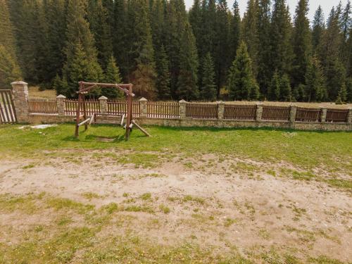 a playground in a field next to a wooden fence at Cabana Laptici - statiunea Pestera-Padina, Bucegi in Sinaia