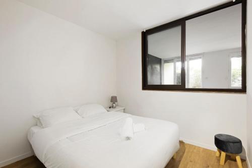 ein weißes Schlafzimmer mit einem weißen Bett und einem Spiegel in der Unterkunft Le Glatigny- Chesnay in Le Chesnay