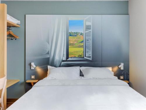 a bedroom with a large white bed and a window at B&B HOTEL Le Creusot Montchanin in Montchanin