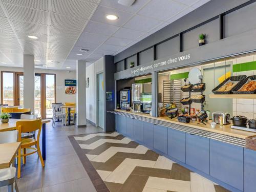 a restaurant with a counter and tables and chairs at B&B HOTEL Le Creusot Montchanin in Montchanin