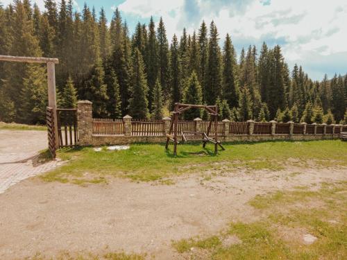 a playground in a field with a fence and trees at Cabana Laptici - statiunea Pestera-Padina, Bucegi in Sinaia