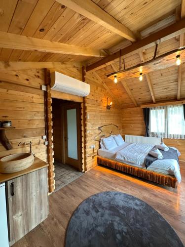 a bedroom in a log cabin with a bed and a sink at Zifona Bungalov in Çamlıhemşin