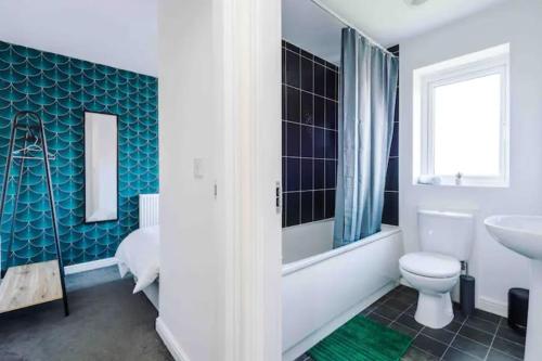 ein Badezimmer mit einem weißen WC und einem Waschbecken in der Unterkunft Spacious 5 Bedroom Home Hosted By MCR Dens in Manchester