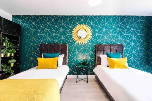 2 Betten in einem Zimmer mit grünen Wänden und gelben Kissen in der Unterkunft Spacious 5 Bedroom Home Hosted By MCR Dens in Manchester