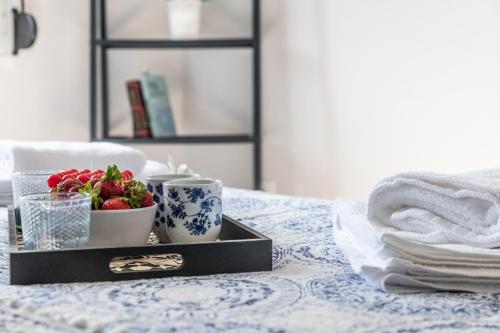 a tray with a bowl of strawberries and cups on a bed at Tsitsanis Home in Tympáki