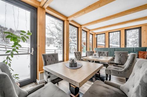 a dining room with tables and chairs and windows at Landhaus Edelweiss in Sankt Leonhard im Pitztal