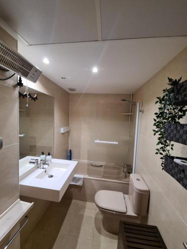 La salle de bains est pourvue d'un lavabo, de toilettes et d'une baignoire. dans l'établissement Apartamento 4 pax Airport Wanda Ifema WiFi, à Madrid