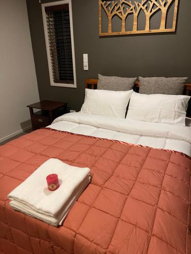 a large bed with a red comforter with a candle on it at Ruth's House Master room with Private shower and toilet in Auckland