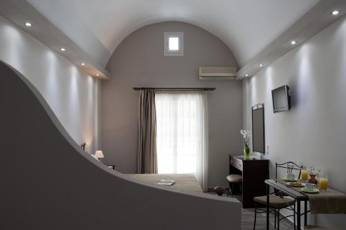 um quarto com uma cama, uma mesa e uma janela em Preka Maria em Kamari