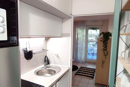 une cuisine avec des armoires blanches et un évier dans l'établissement RAVAS Studio climatisé terrasse proche commerces, à Montpellier