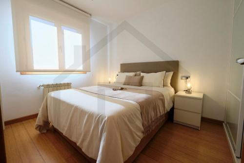 a bedroom with a large white bed and a window at Apartamento La Muralla - Gijón in Gijón