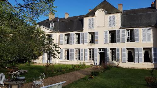 uma grande casa branca com um quintal com cadeiras e mesas em Chambre aux coccinelles em Cosne-Cours-sur-Loire