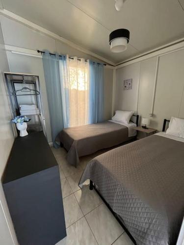 Habitación pequeña con 2 camas y ventana en Elia’s house, en Ligia