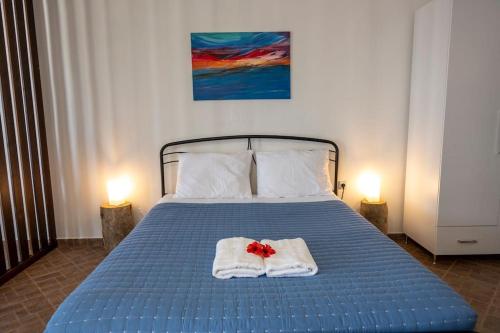 ein blaues Bett mit Handtüchern und einer roten Blume darauf in der Unterkunft Kalithea Studio 2 in Palekastro