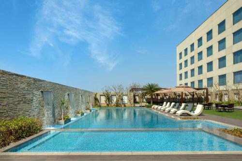 a swimming pool with chairs and a building at Radisson Blu Faridabad in Faridabad