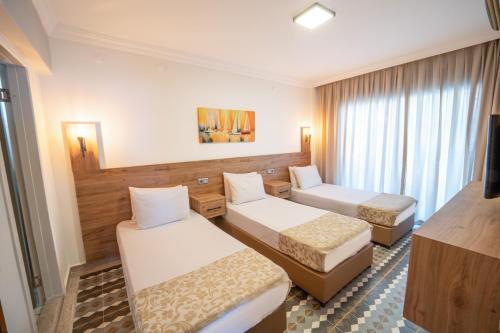 マルマリスにあるModa Beach Hotelのベッド2台とテレビのあるホテルの部屋