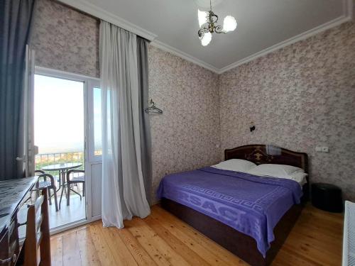 1 dormitorio con cama morada y balcón en Guest House Maria, en Signagi
