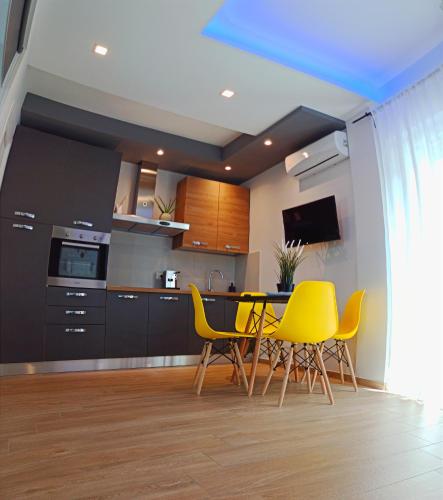 a kitchen with yellow chairs and a table and cabinets at Kemilia Matera in Matera