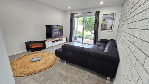 a living room with a black couch and a tv at Selenas @ Culburra Beach in Culburra Beach