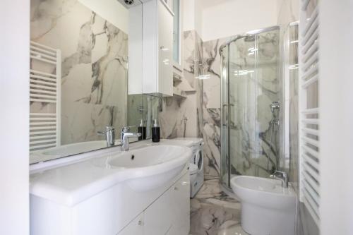 La salle de bains blanche est pourvue d'un lavabo et d'une douche. dans l'établissement Casa Vacanza " La Rosa " Imperia Liguria, à Imperia