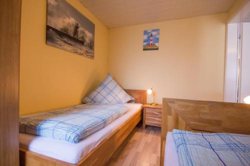 ビューズムにあるHaus-Karin-Ferienwohnung-2の小さなベッドルーム(ベッド2台、ナイトスタンド付)